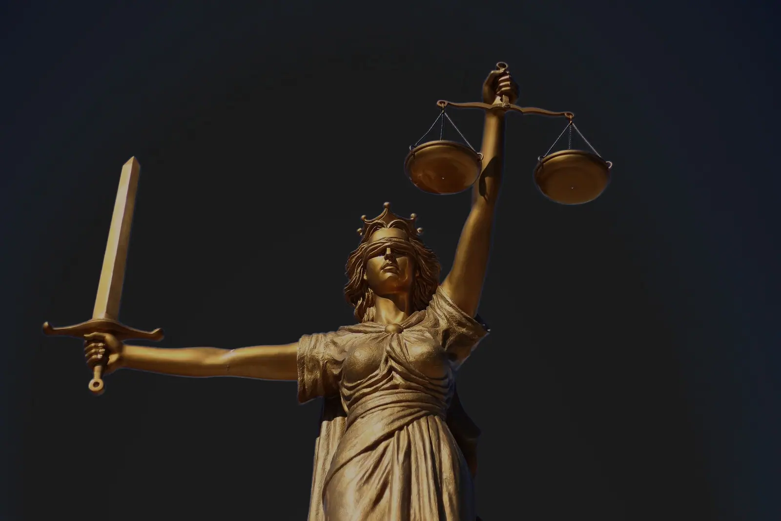 Estátua da Justiça com a balança, em fundo escuro